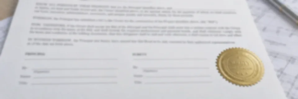 A bid bond form on a desk beside rolled drawings, signed and sealed with a gold surety seal, with a building frame under construction behind it